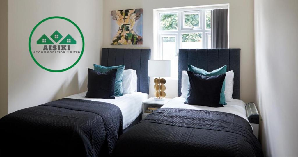 - 2 lits dans une chambre avec un panneau mural dans l'établissement Aisiki Living at Alexandra Road, 2-Bedroom & 2-Bathroom with King or Twin Beds with Free Wi-Fi & Parking Space, à Watford
