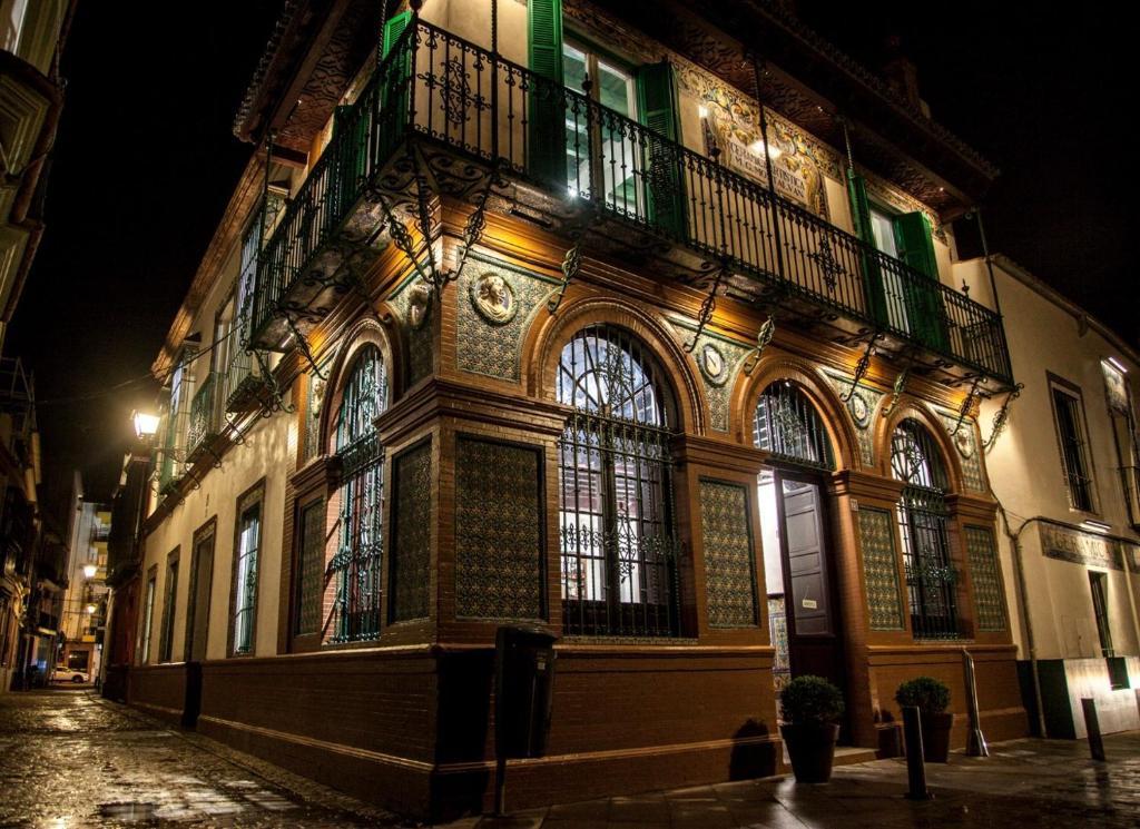 a building with a balcony on a street at night at HOTEL TRIANA MONTALVAN in Seville