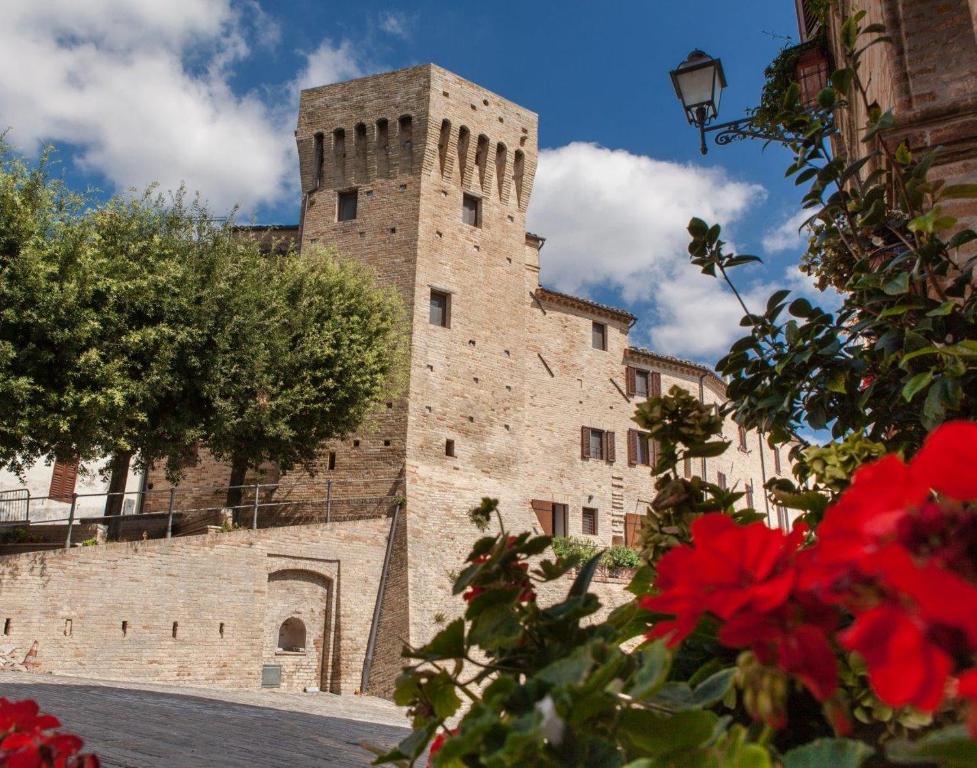ein großes Steingebäude mit einem Turm in einer Stadt in der Unterkunft MarcheAmore - Torre da Bora, Luxury Medieval Tower in Magliano di Tenna