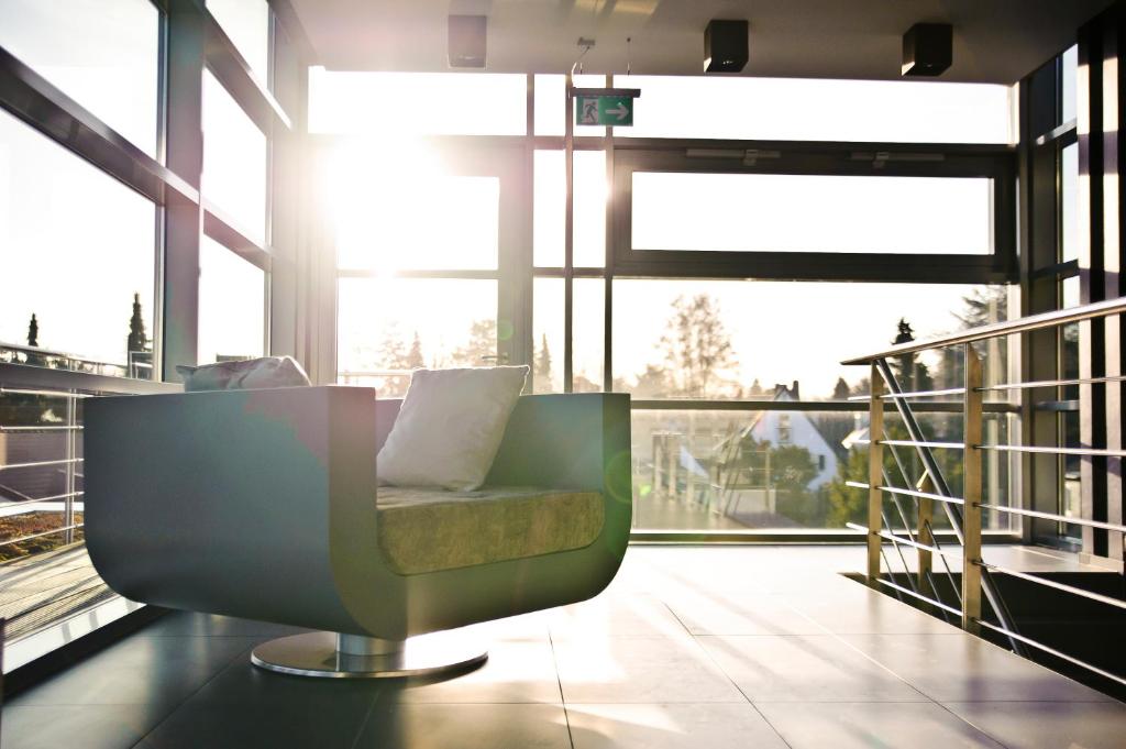 a green chair in a room with large windows at Hotel Rosenmeer in Mönchengladbach
