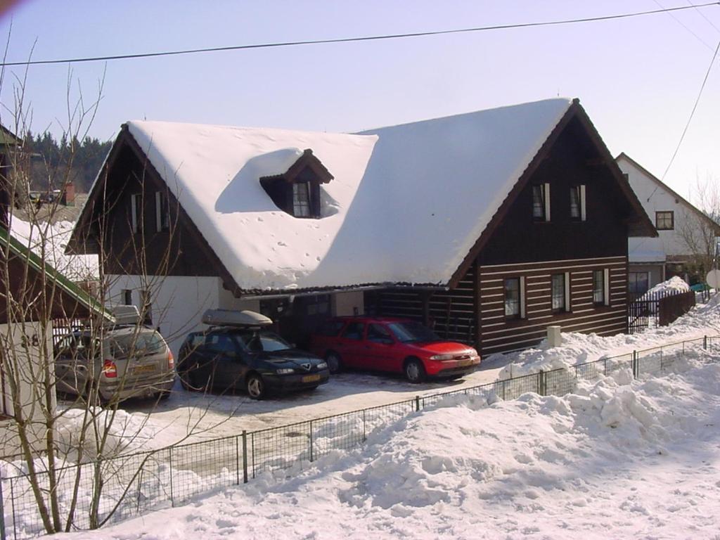domek z bali z samochodami zaparkowanymi na śniegu w obiekcie Vakantiehuis Cerny Dul 259 w mieście Cerny Dul
