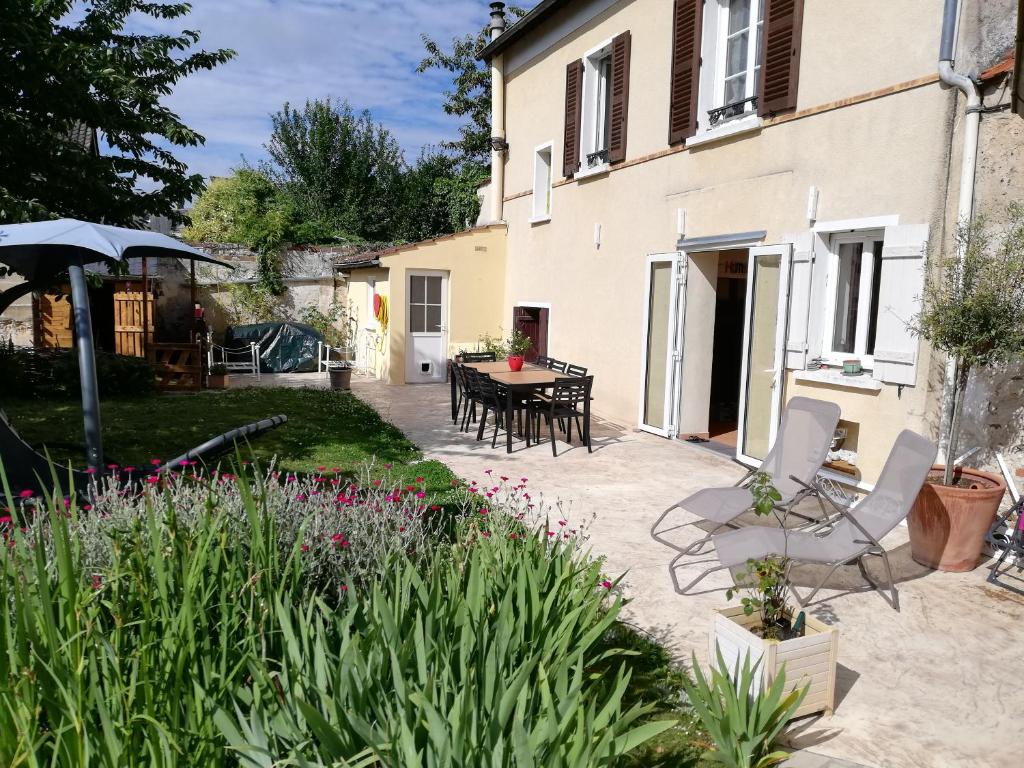 a patio with a table and chairs in a yard at Celine'Home in Saint-Germain-sur-Morin