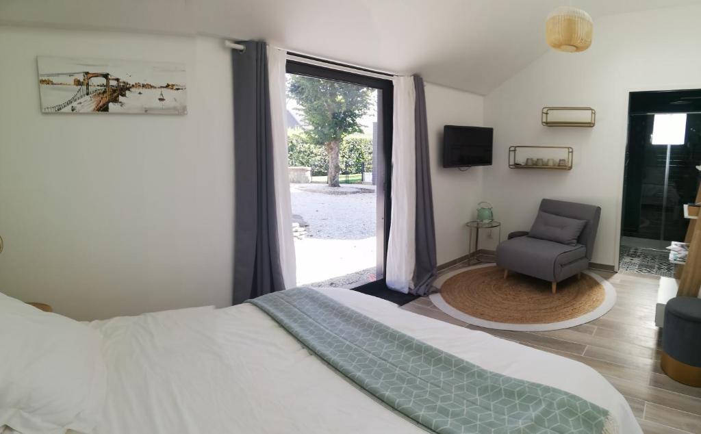 1 dormitorio con 1 cama, 1 silla y 1 ventana en Villa Moya, dependance privée Piscine & Spa, en Châteauneuf-sur-Loire