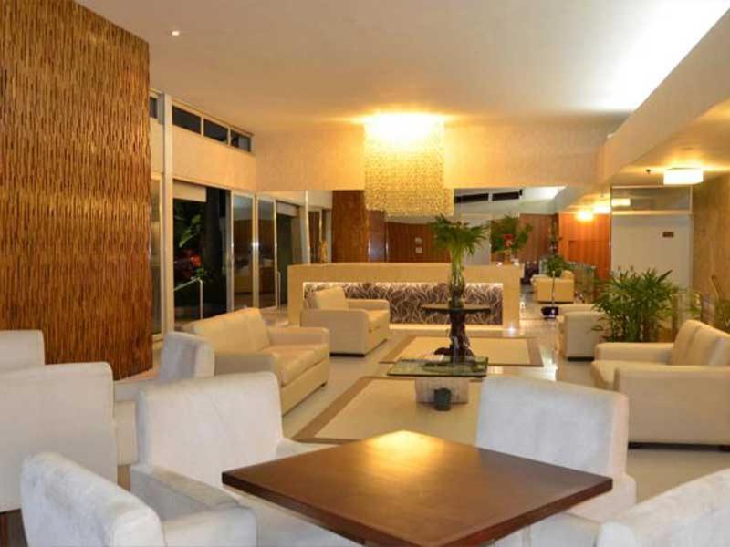 una sala de estar con sofás blancos y una mesa. en Arituba Park Hotel, en Natal