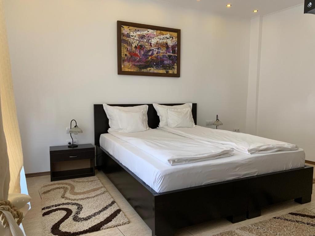ein Schlafzimmer mit einem Bett mit einem Bild an der Wand in der Unterkunft CHIC CITY Rooms in Sighişoara