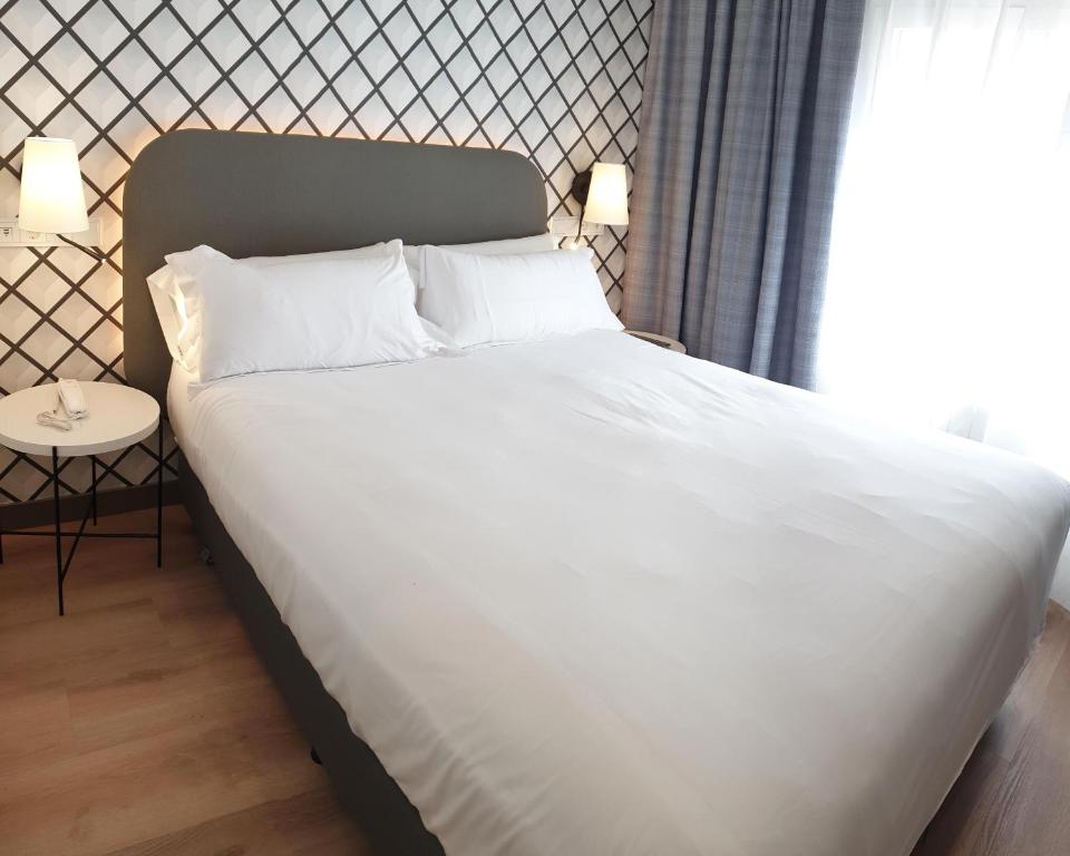 1 cama con sábanas blancas y almohadas en una habitación en Rice Reyes Católicos, en Burgos