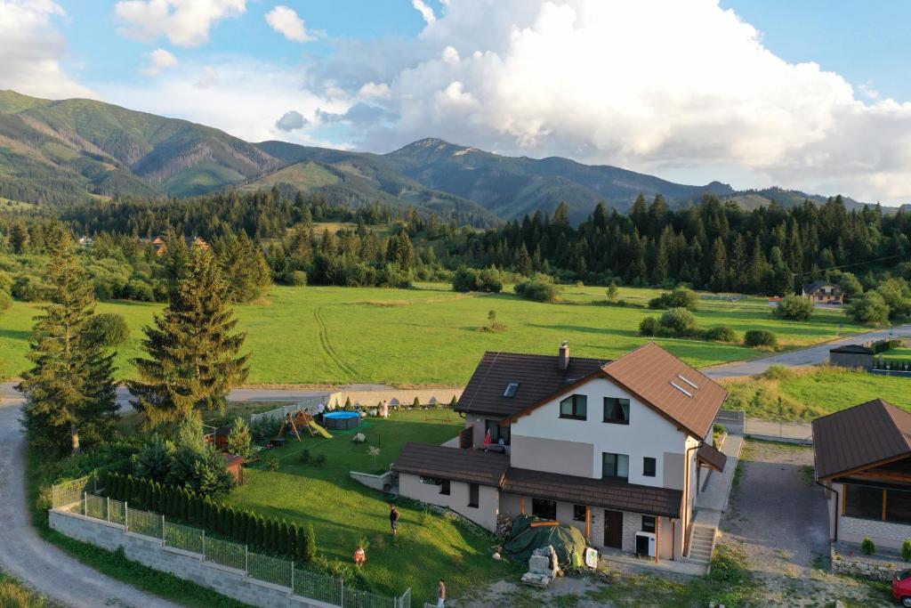 ein Haus auf einem Feld mit Bergen im Hintergrund in der Unterkunft Apartmán pod Sivým vrchom in Zuberec