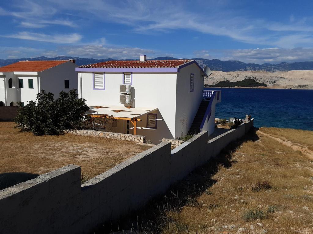 una casa junto al agua con una valla en APARTAMENTOS AROMA, en Pag