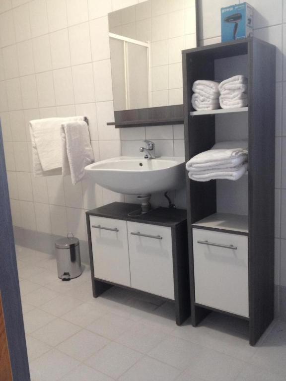 łazienka z umywalką i półką z ręcznikami w obiekcie APARTAMENTOS AROMA w mieście Pag