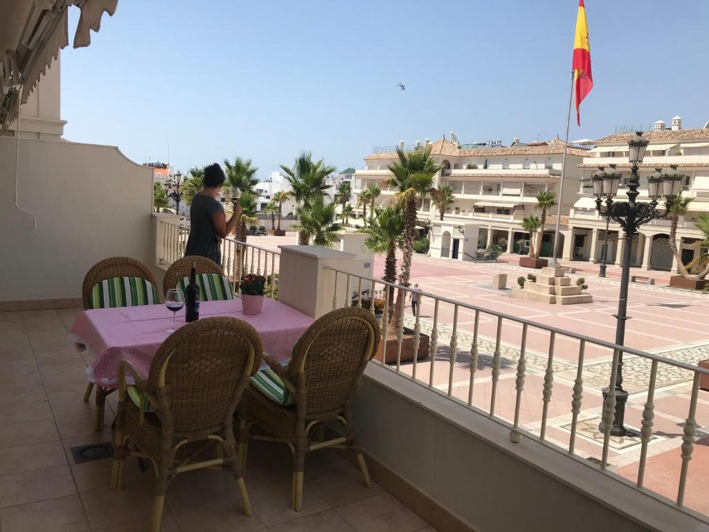 a man standing on a balcony with a table and chairs at Apartamento Plaza España in Nerja