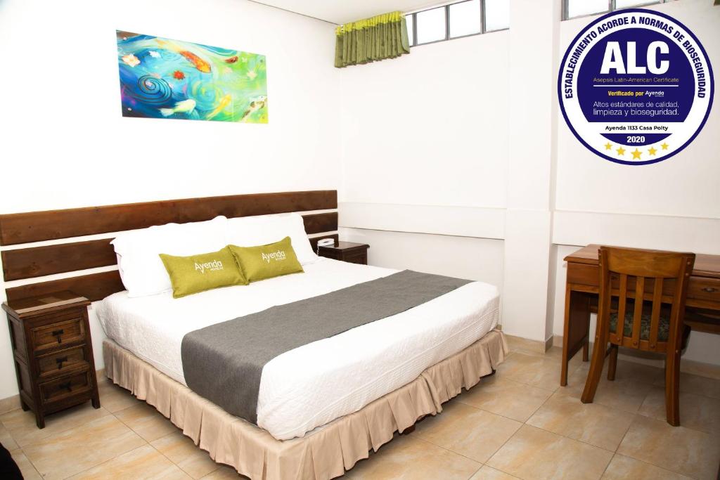1 dormitorio con cama, escritorio y cartel en Ayenda 1133 Casa Polty, en Manizales