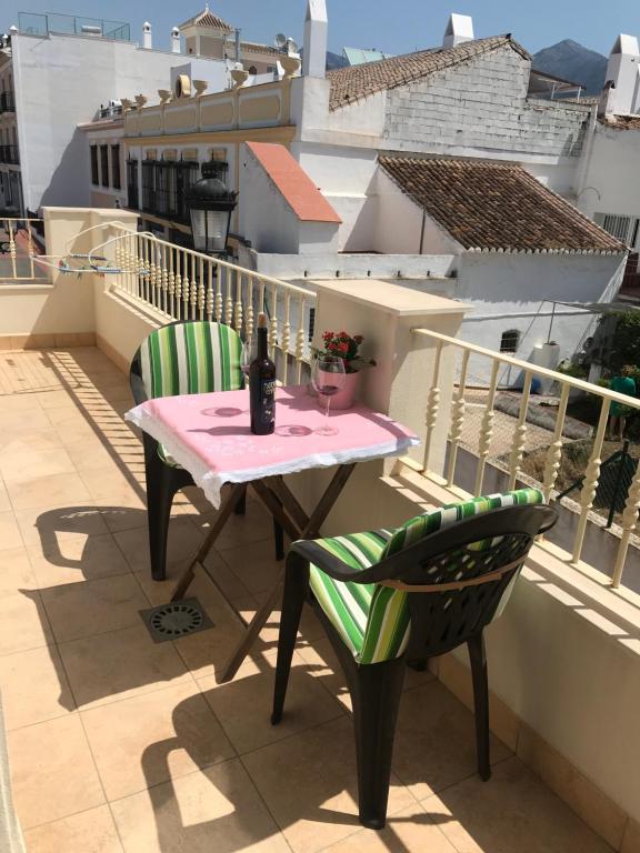 a table and chairs on a balcony with a bottle of wine at PLAZA DE ESPAÑA 1 DORMITORIO in Nerja