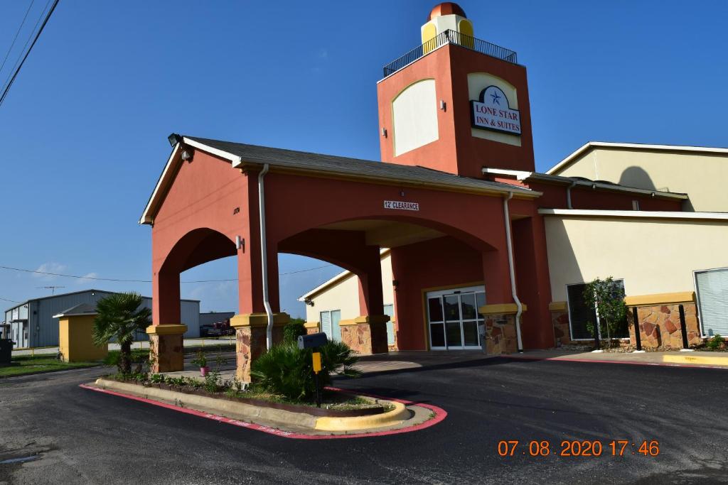 a red building with a clock tower on a street at Lone Star Inn & Suites in Groesbeck