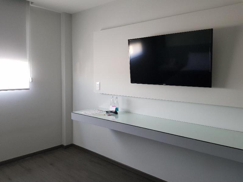 A wall-mounted television above a long, narrow floating desk.