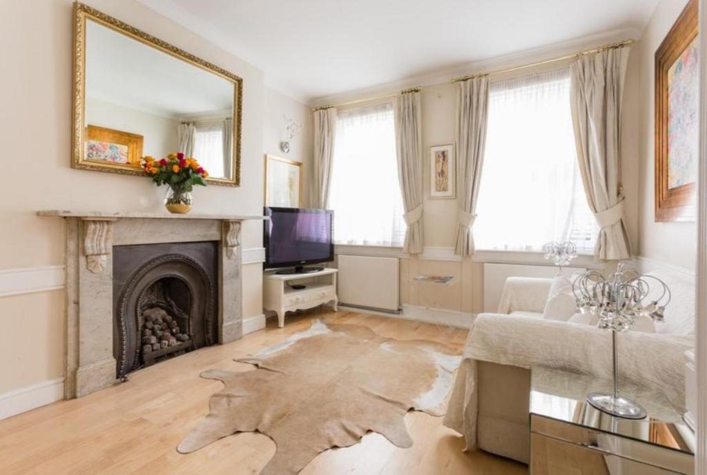 Una sala de estar con un sofá y una chimenea. en Marylebone Luxury 3BR Flat Elegant Central Gem, en Londres