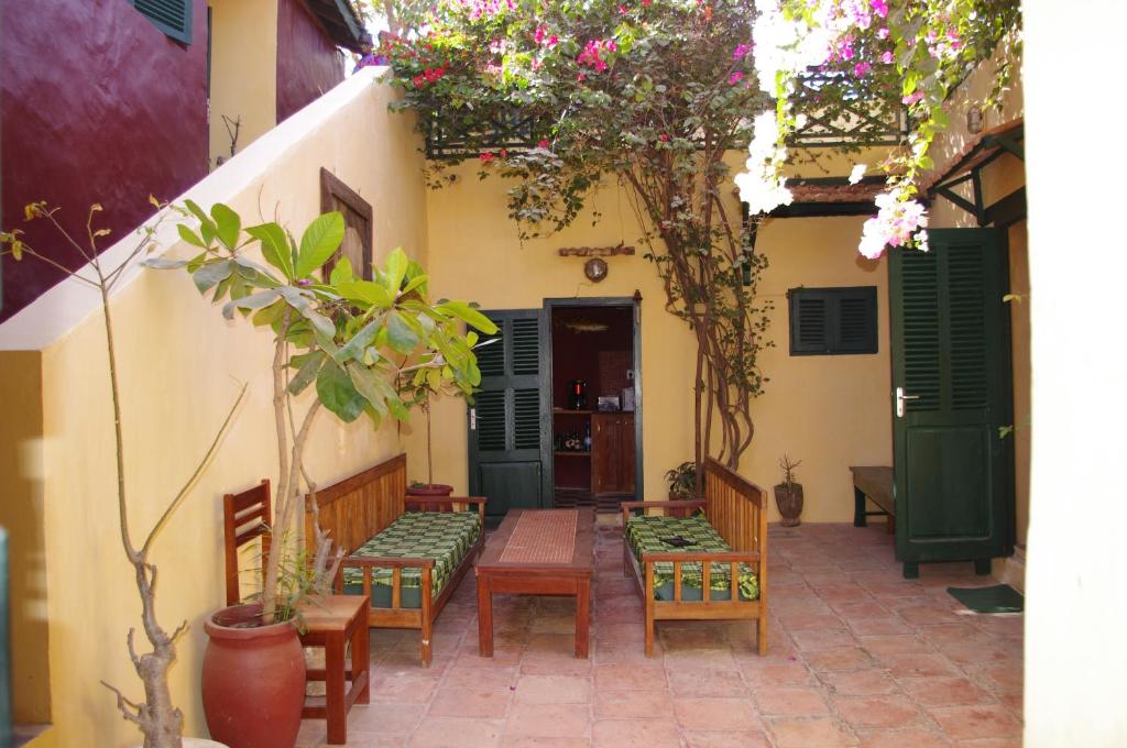 a patio with benches and chairs in a building at Maison Augustin LY in Gorée