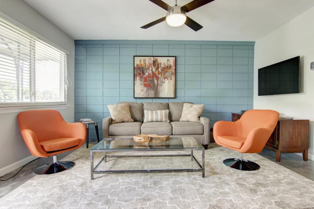 a living room with a couch and two orange chairs at South River Condo in Austin