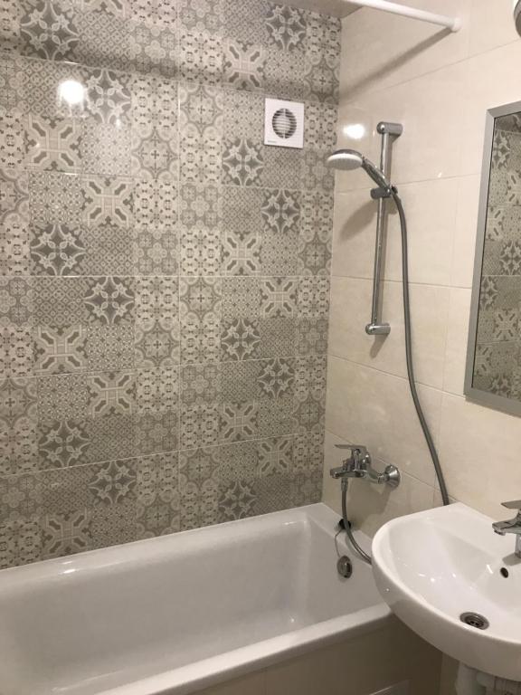 Apartment Metro Minska في كييف: حمام مع حوض وحوض استحمام ومغسلة