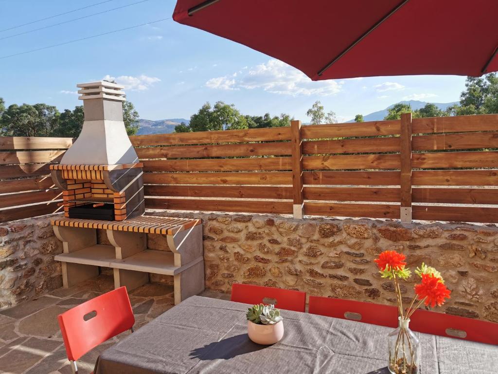 a patio with a table and an umbrella and a grill at CASITAS PINILLA DEL VALLE in Pinilla del Valle