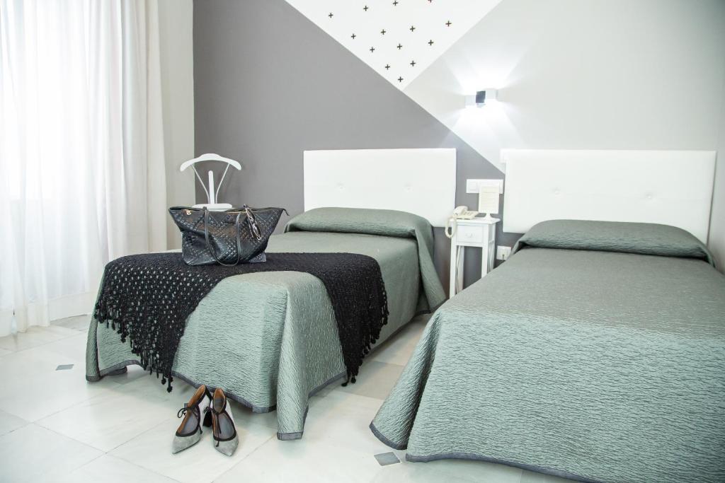 ein Schlafzimmer mit 2 Betten und Schuhen auf einem Tisch in der Unterkunft Casa Palacio Don Pedro in Sevilla