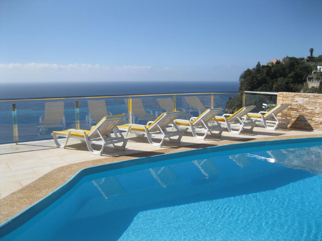 a swimming pool with chairs and the view of the ocean at Villa Isabela - Car Rental for Free in Caniço