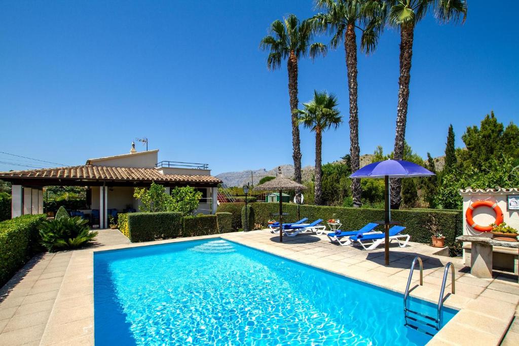 a swimming pool with palm trees and a house at Pantina in Pollença