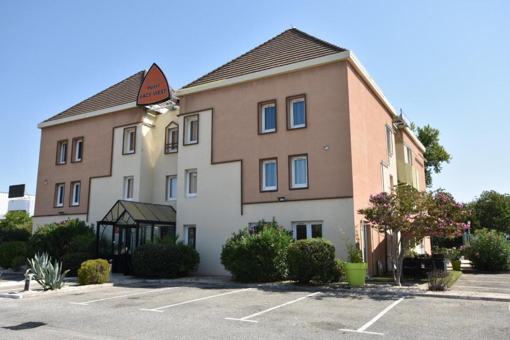 a large building with a parking lot in front of it at Face West Le Pontet in Le Pontet
