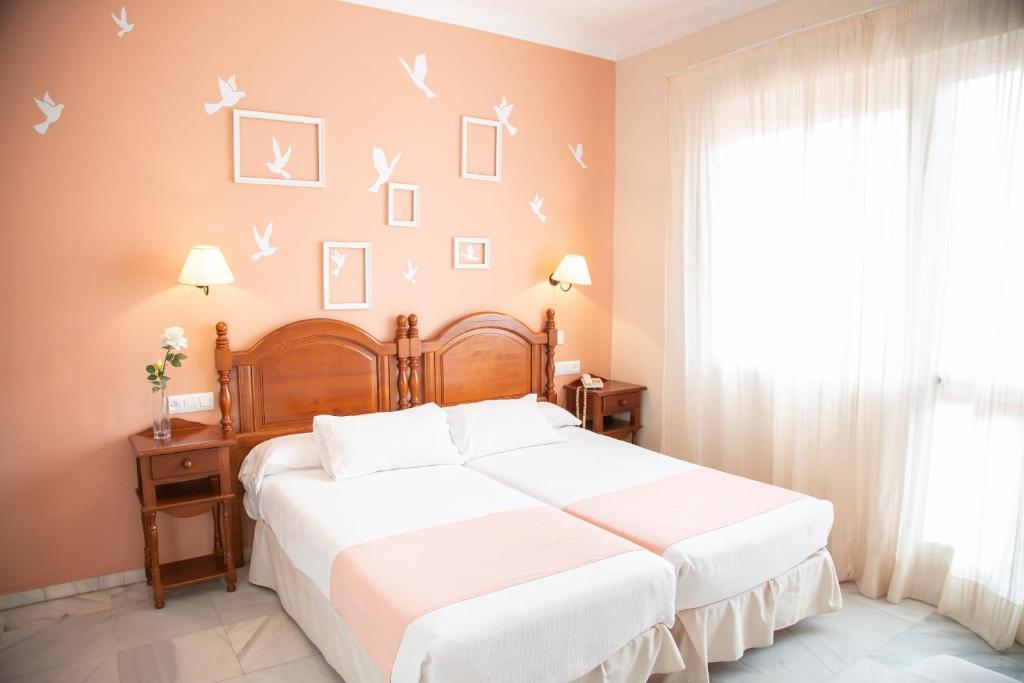 1 dormitorio con 1 cama con sábanas blancas y pájaros en la pared en Casa Palacio Don Pedro en Sevilla