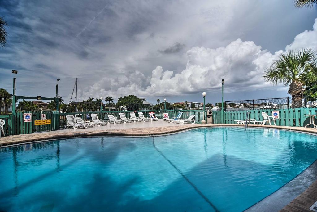 duży basen z krzesłami i niebieskim płotem w obiekcie Coastal Condo with Pool, Walk to Clearwater Beach! w mieście Clearwater Beach