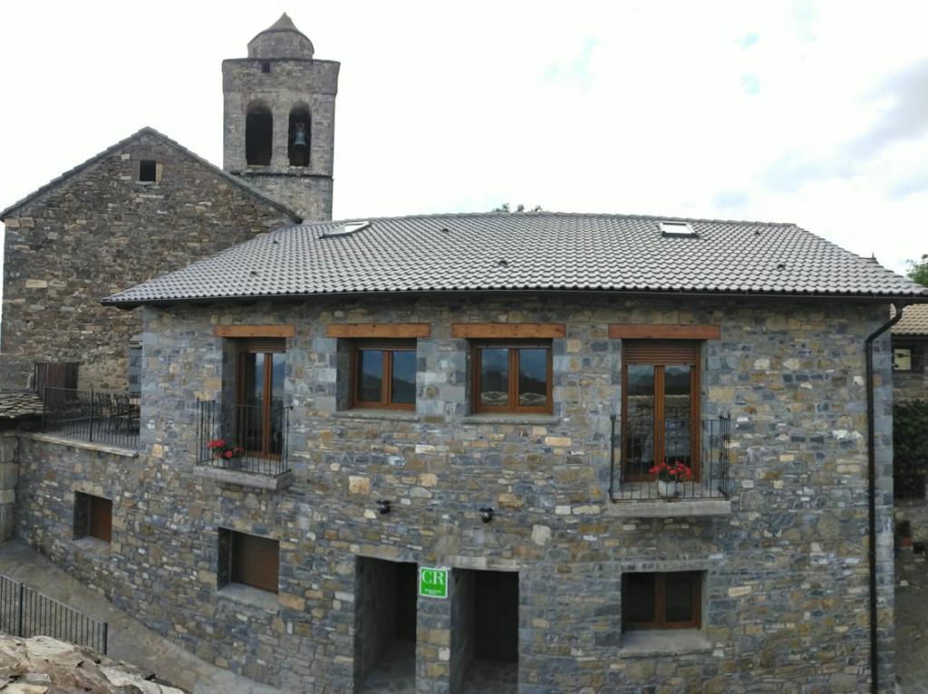 een stenen gebouw met een klokkentoren op de achtergrond bij Casas Rurales Bestue-Ordesa in Bestué