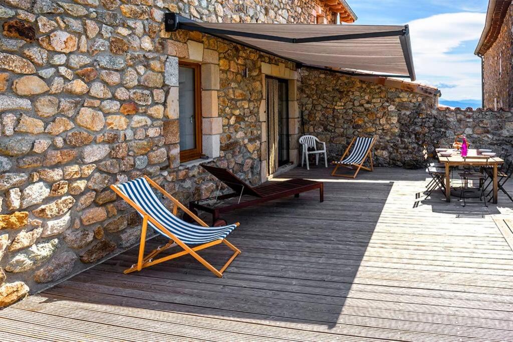 a wooden deck with chairs and an umbrella on a building at Rouretord Hirondelle in Gilhac-et-Bruzac