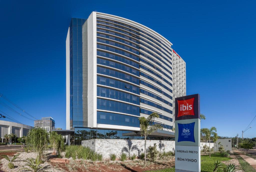 a tall building with a bus sign in front of it at ibis Budget Ribeirão Preto Vila do Golf in Ribeirão Preto