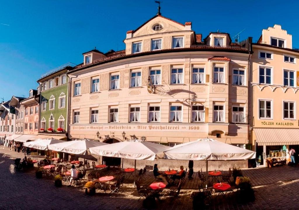 un gran edificio con mesas y sombrillas delante en Posthotel Kolberbräu, en Bad Tölz