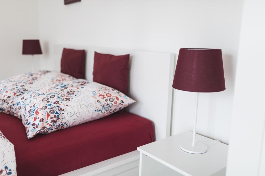 um quarto com uma cama vermelha com uma almofada e um candeeiro em Apartment Falkenstein em Königstein im Taunus