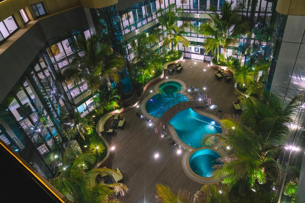 an overhead view of a pool in a building with palm trees at Andalus Habitat Hotel in Jeddah