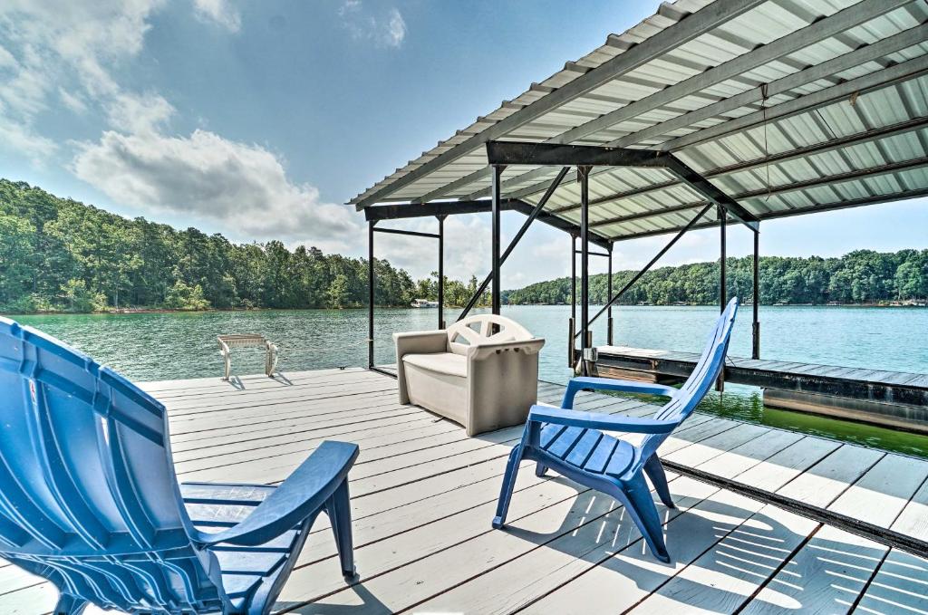 twee blauwe stoelen op een houten terras naast het water bij Spacious Lake Hartwell Home with Private Boat Dock! in Anderson