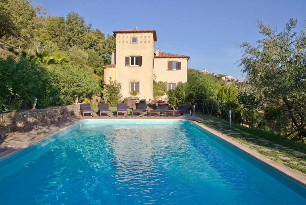 ein Pool mit Stühlen und ein Haus im Hintergrund in der Unterkunft Borgo Riccio in Torchiara