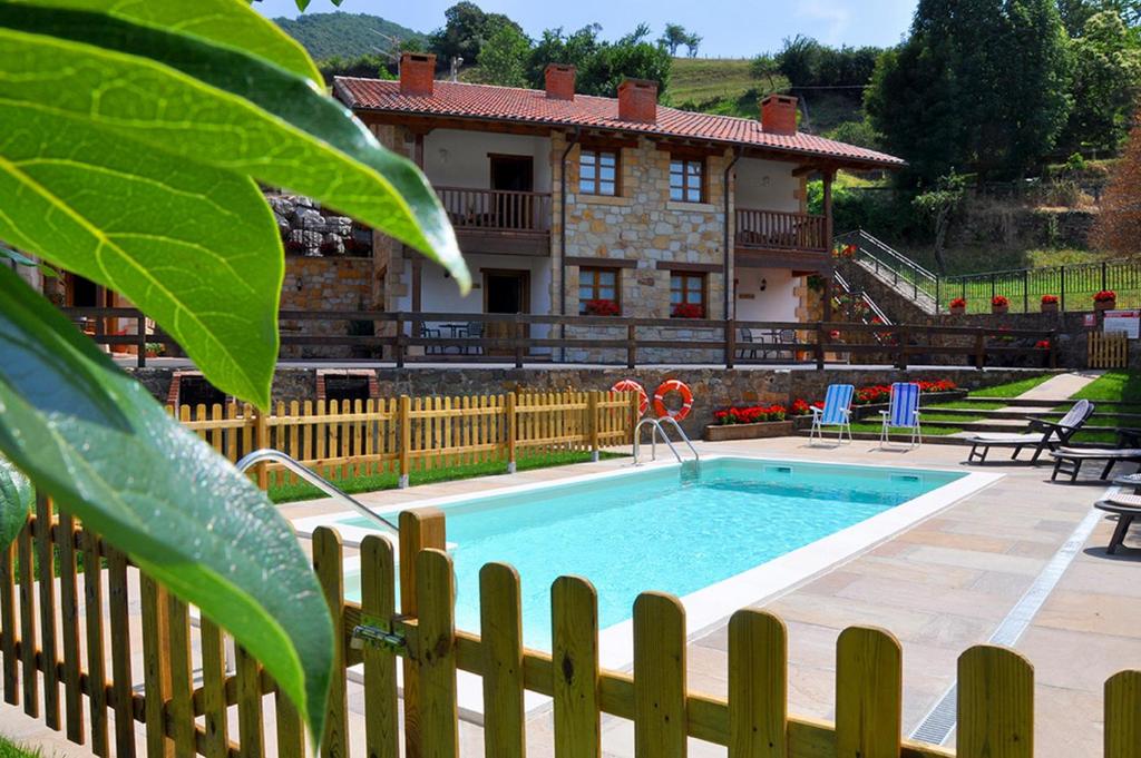 une maison avec une piscine en face d'une clôture dans l'établissement Casa Rural Los Llares, à Lerones