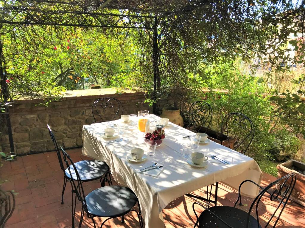 uma mesa com uma toalha de mesa branca e cadeiras num pátio em Dimora Belvedere em Montecatini Terme