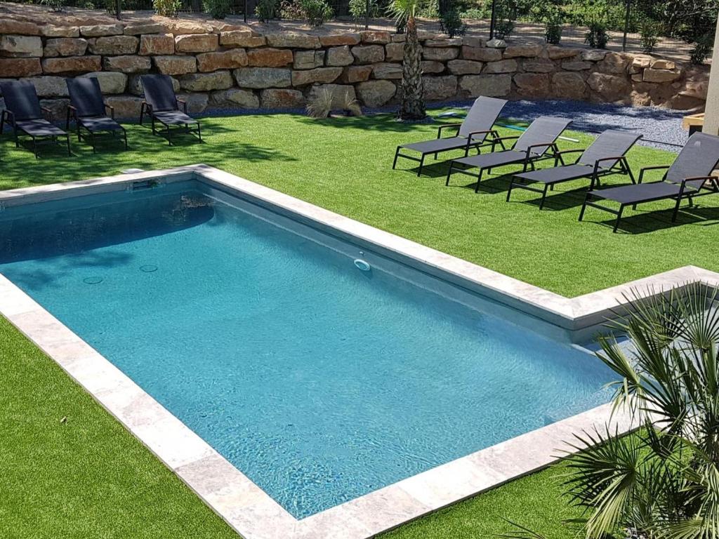 uma piscina com cadeiras e um quintal com uma parede de retenção em Villa Saona em Plan-de-la-Tour
