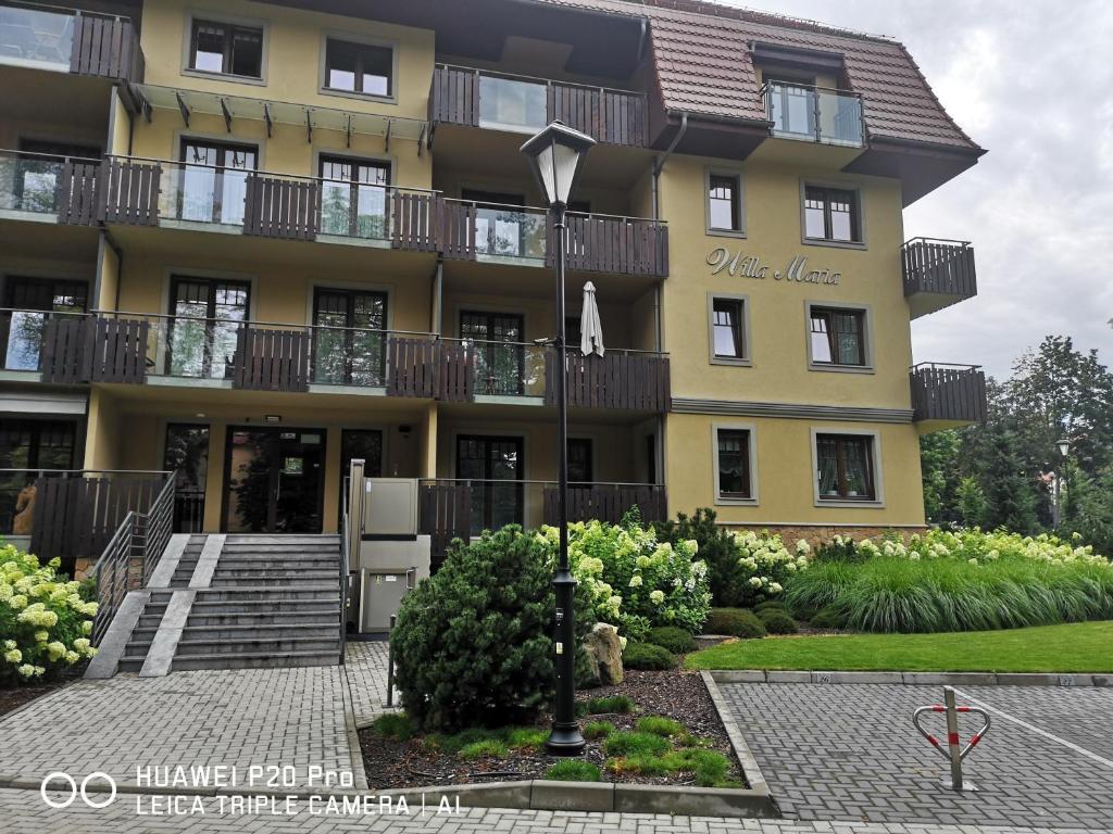un grand bâtiment jaune avec un escalier devant. dans l'établissement Apartament Zuza, à Polanica-Zdrój