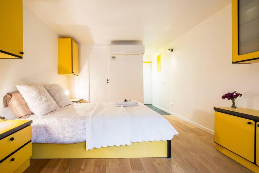 a bedroom with a white bed and yellow cabinets at CHARMING LE MARAIS RETRO in Paris