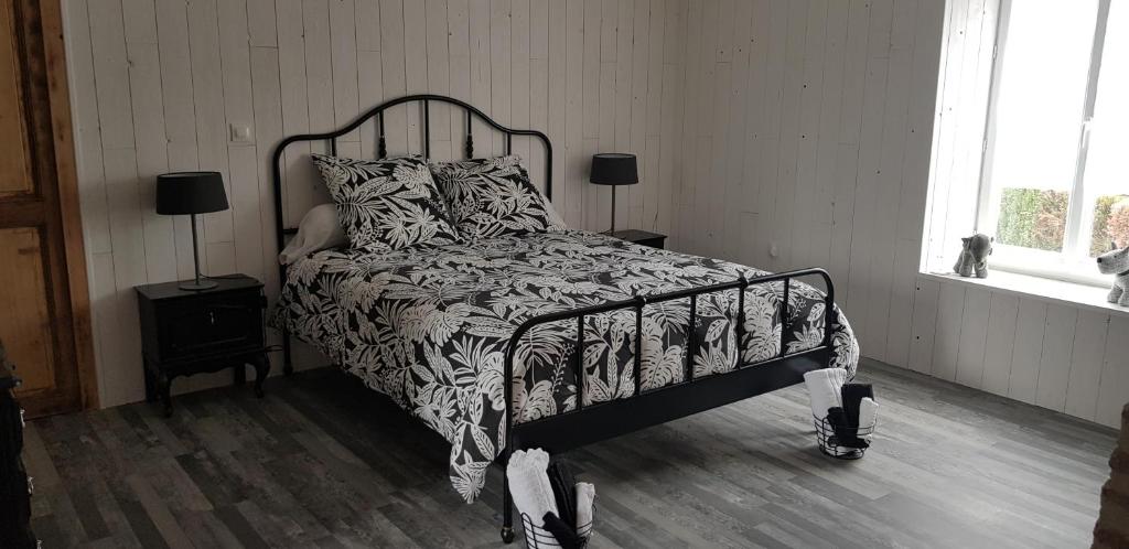 a bedroom with a bed with a black and white comforter at La Maison Josnes de Mady in Josnes