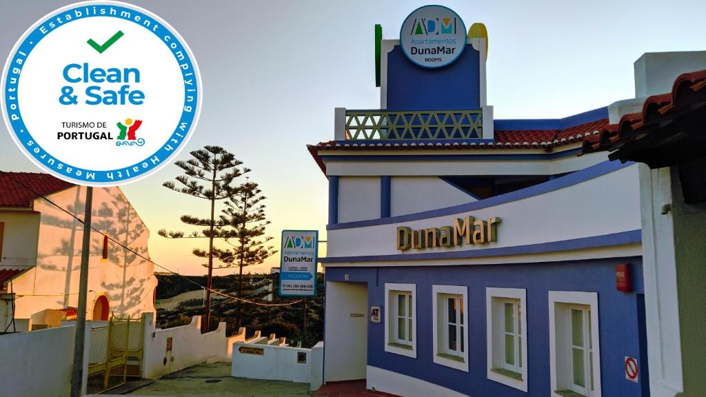 un edificio azul y blanco con un cartel en él en Apartamentos Dunamar en Vila Nova de Milfontes