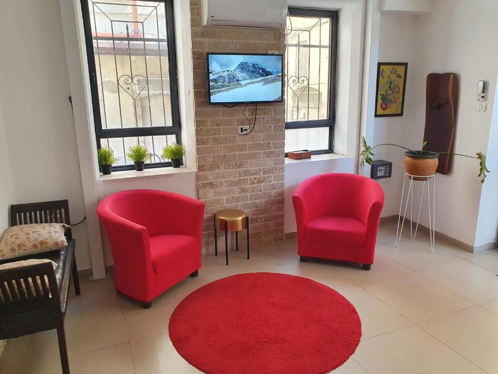 ein Wohnzimmer mit 2 Stühlen und einem roten Teppich in der Unterkunft BE ME Hotels and Hostels HAIFA ART in Haifa