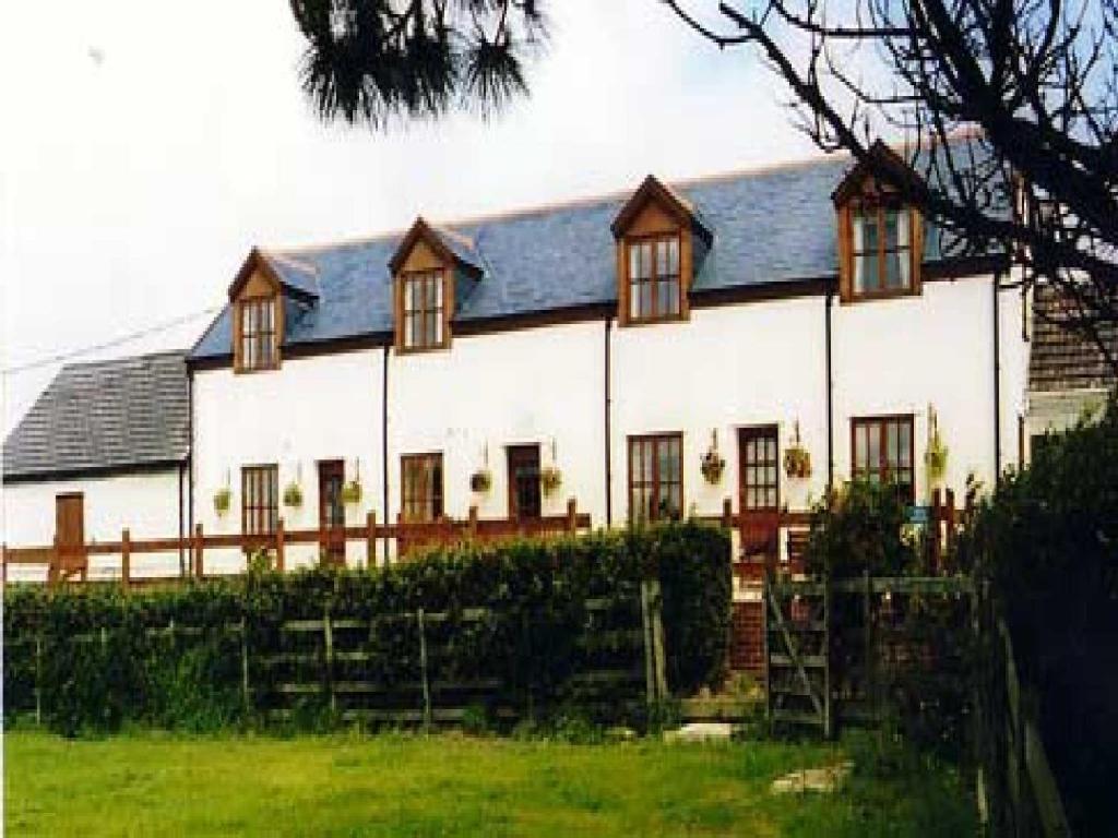 a large white house with a fence in front of it at Mullacott Farm in Ilfracombe