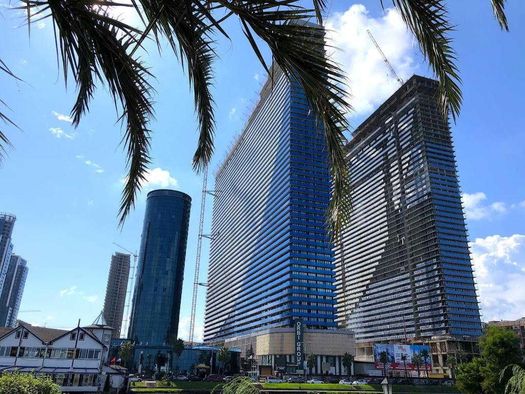 two tall buildings in a city with a palm tree at Orbi City in Batumi