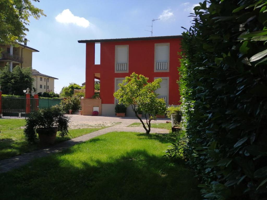 ein rotes Haus mit einem Baum davor in der Unterkunft bellaria in Voghera