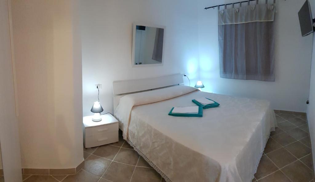 Luxury apartament Alice في أولبيا: غرفة نوم مع سرير أبيض مع منضدة وسرير six sidx