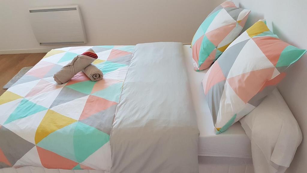 uma cama com um edredão colorido e almofadas em Maison Neuve Moderne em Fresney-le-Vieux